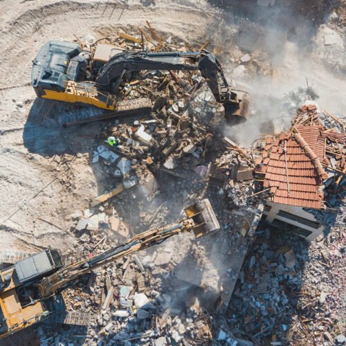 Urban Renewal‎. Urban Regeneration. Demolition of a building for new construction. Dismantling of a house. Excavator demolishing barracks for new construction project. . High quality photo