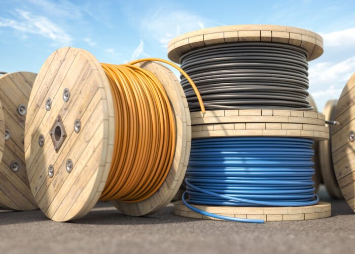 Wire electric cable of different colors on wooden coil or spool in warehouse. 3d illustration