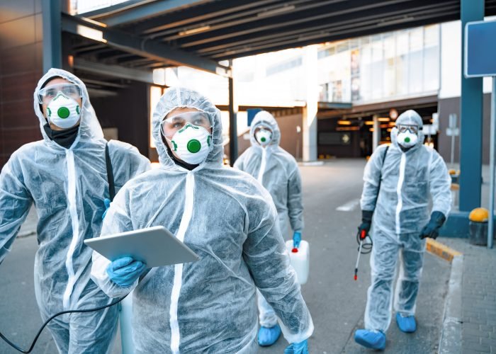 Healthcare workers wearing hazmat suits working together during an outbreak in the city