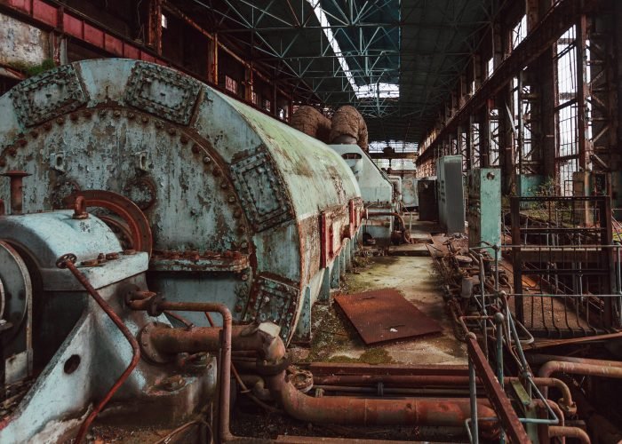 Rusty turbine generator. Abandoned destroyed by war and overgrown by plants and moss machinery of Tkvarcheli (Tquarchal) power plant, Abkhazia, Georgia.